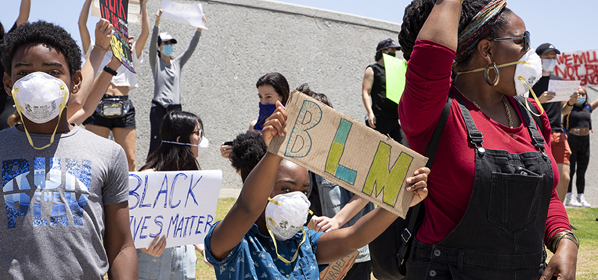 Two young Black children holding up protest signs